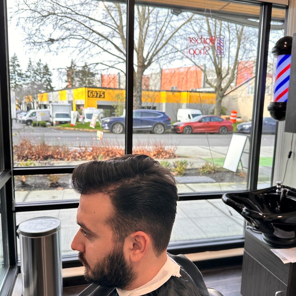 Men's scissor haircut with a shaped full beard, profile by the window at European Barber in Redmond